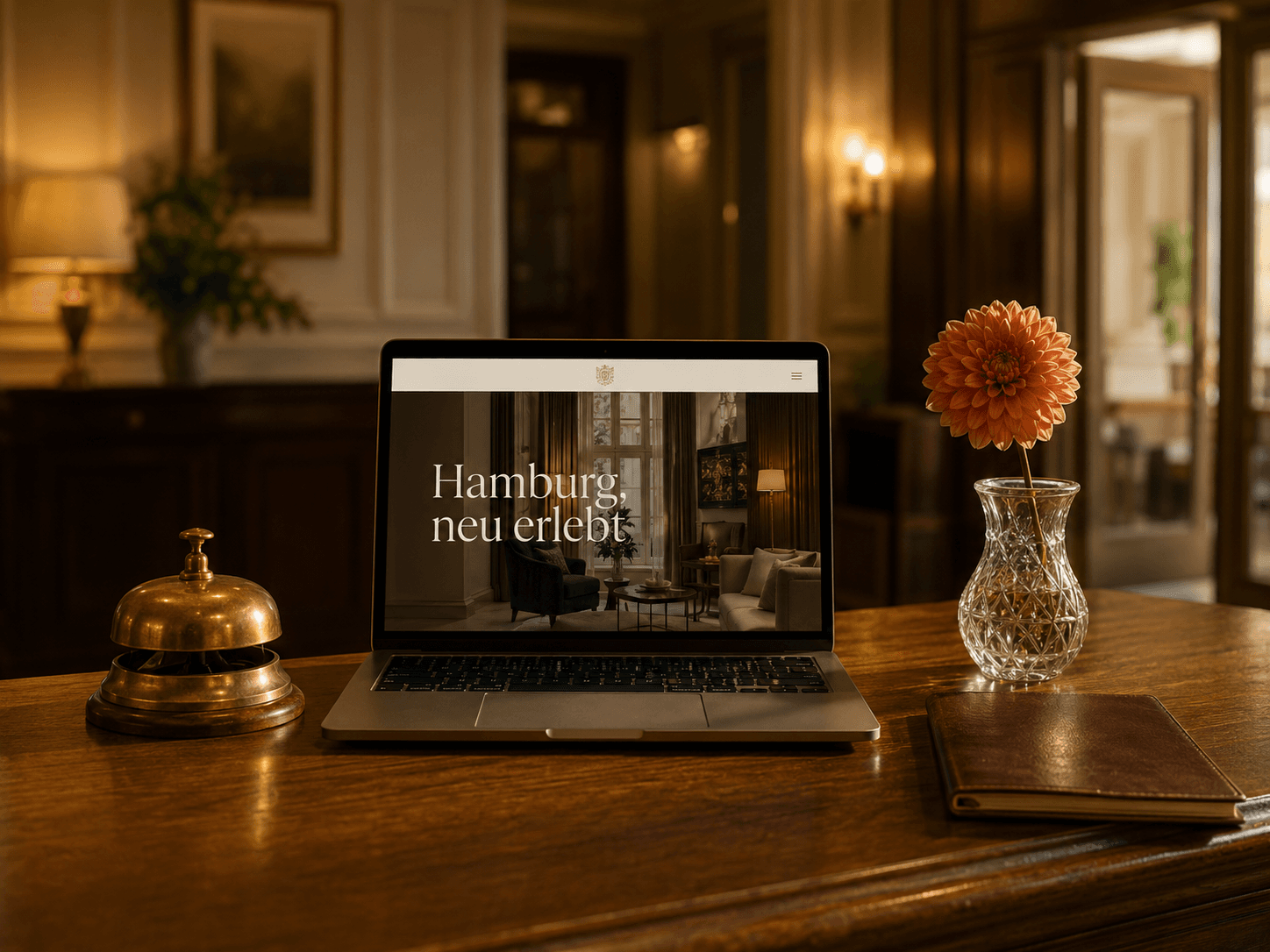 Boutique-Hotel-Website von Sitalo („Hamburg, neu erlebt") auf einem Laptop, Messing-Klingel und Blumenstrauß auf einem polierten Empfangstresen.